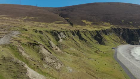 The-cliffs-at-Keel-beach-during-a-sunny-spring-day,-revealing-the-beach,-drone-shot