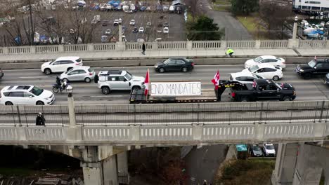 Pickup-Fahrzeug,-Das-Einen-Pritschenwagen-Mit-Kanadischen-Flaggen-Und-Einem-Banner-Mit-Endmandaten-Abschleppt