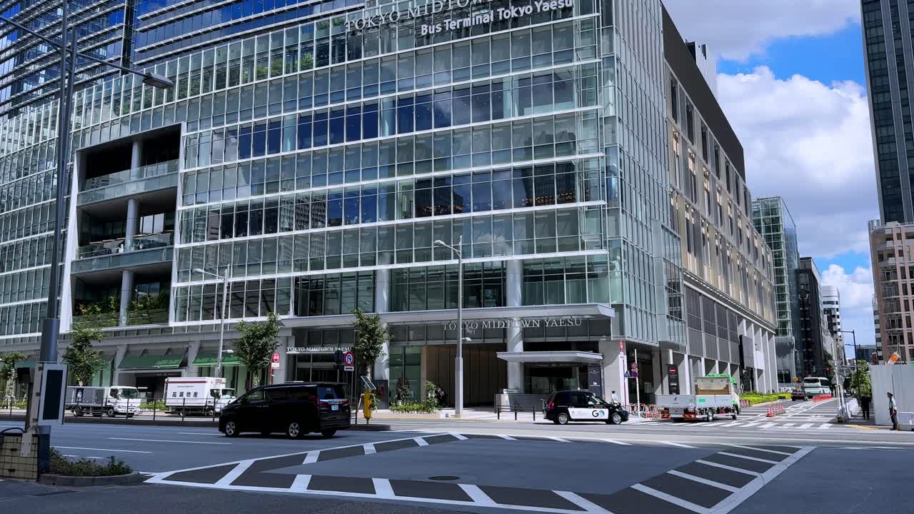 A Kintetsu bus parked outside modern glass buildings at Tokyo Station under a blue sky