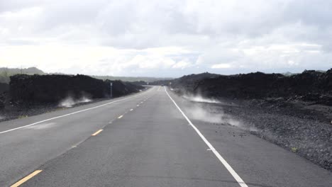 ángulo bajo a lo largo de la carretera a través del parque nacional del volcán con vapor saliendo de la roca de magma caliente hacia la carretera