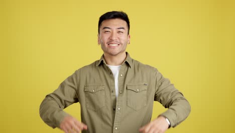 excited asian man celebrating on a yellow background