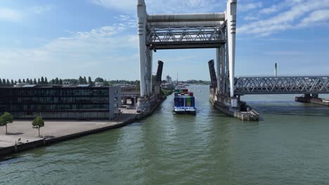 container vessel passes under the railway bridge across oude maas river, dordrecht