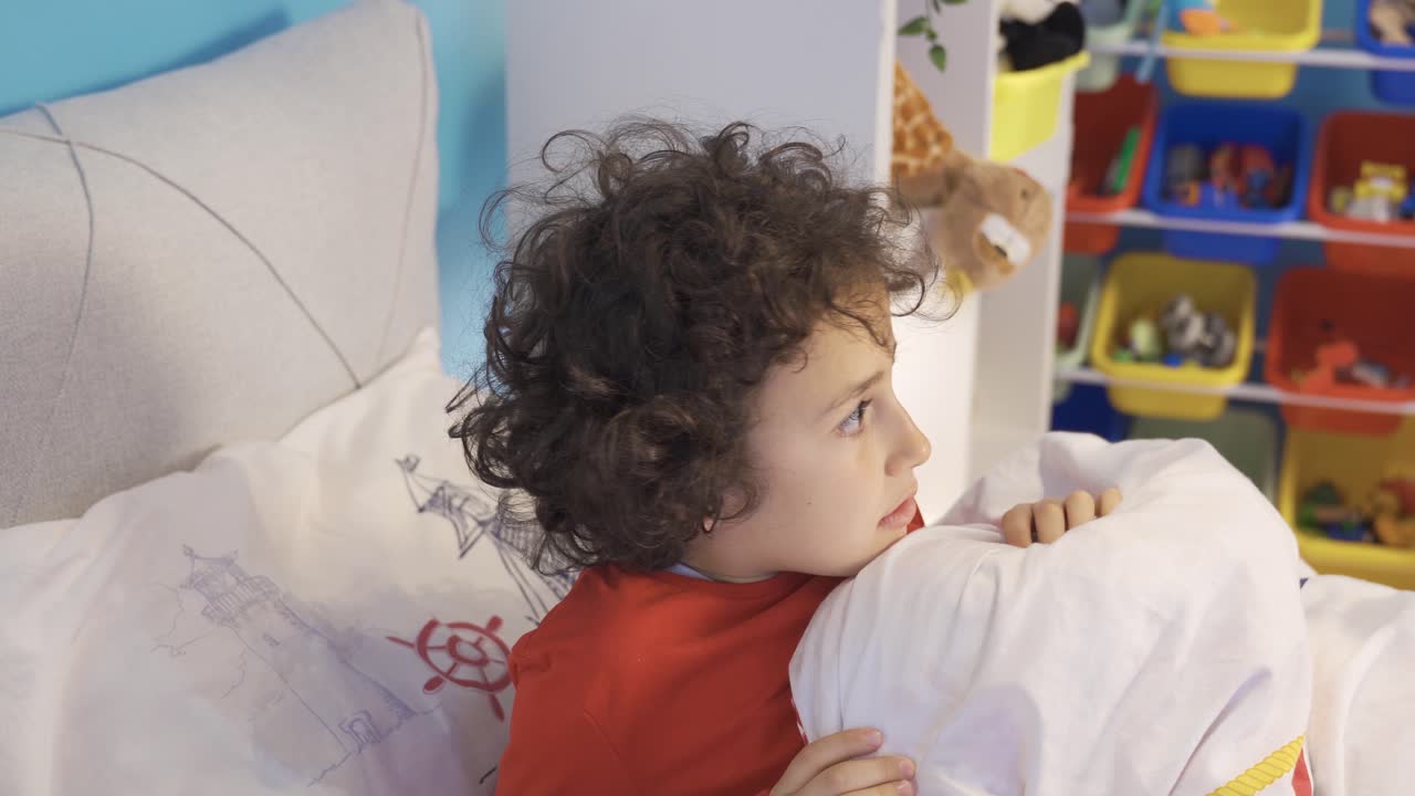 침대에서 겁에 질린 소년은 괴물에 의해 방해받았습니다.