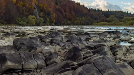stone bank against colorful trees growing on hills in autumn