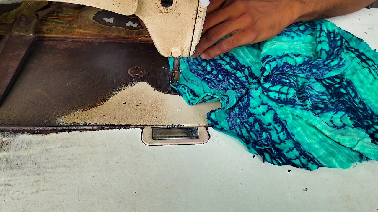 Skräddare syr färgglatt tyg på en industriell symaskin, visar klädtillverkning, textilproduktion, klädsömnad, hantverk, handgjorda kläder och småföretagsarbete.