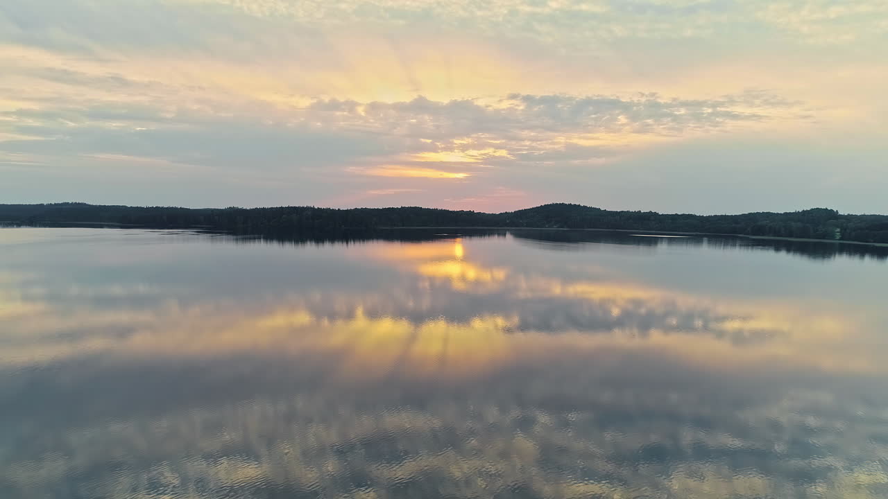 vuelo aéreo sobre un lago tranquilo con reflejo en la superficie de la luz del sol y las nubes en el cielo