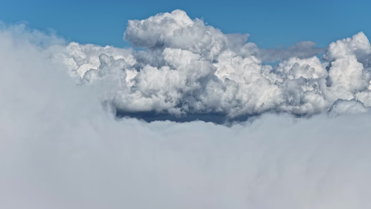 Dramatic cumulus cloud formations rising above a dense lower cloud layer