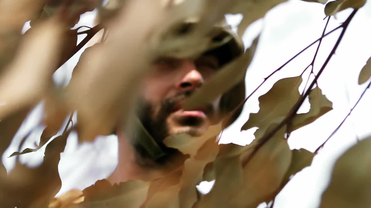 hombre militar de pie detrás de las hojas