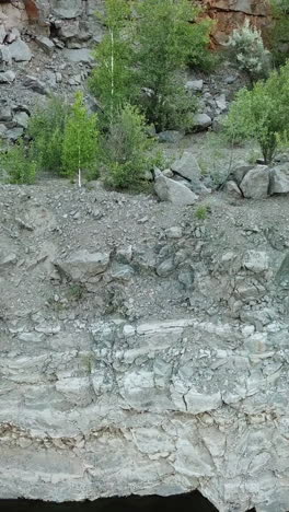 aerial view of a tourist walks along the rocky shore of a lake. traveler on the cliff. camping season vertical video