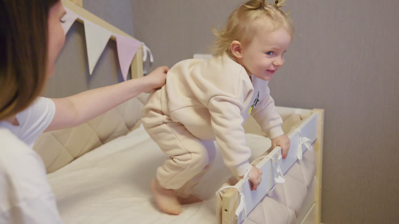 Happy Baby Learning to Stand Up in Crib with Mother's Help