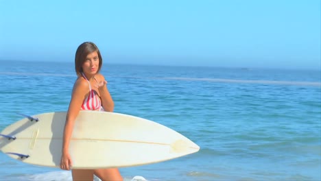 pretty darkhaired woman posing with her surfboard