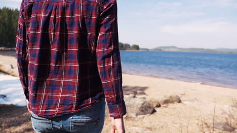 girl walking with a trangia portable stove on a sunny beach at the lake