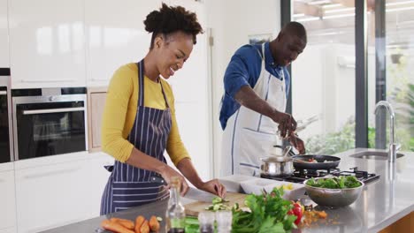 Video-of-happy-african-american-couple-preparing-meal-together-in-kitchen