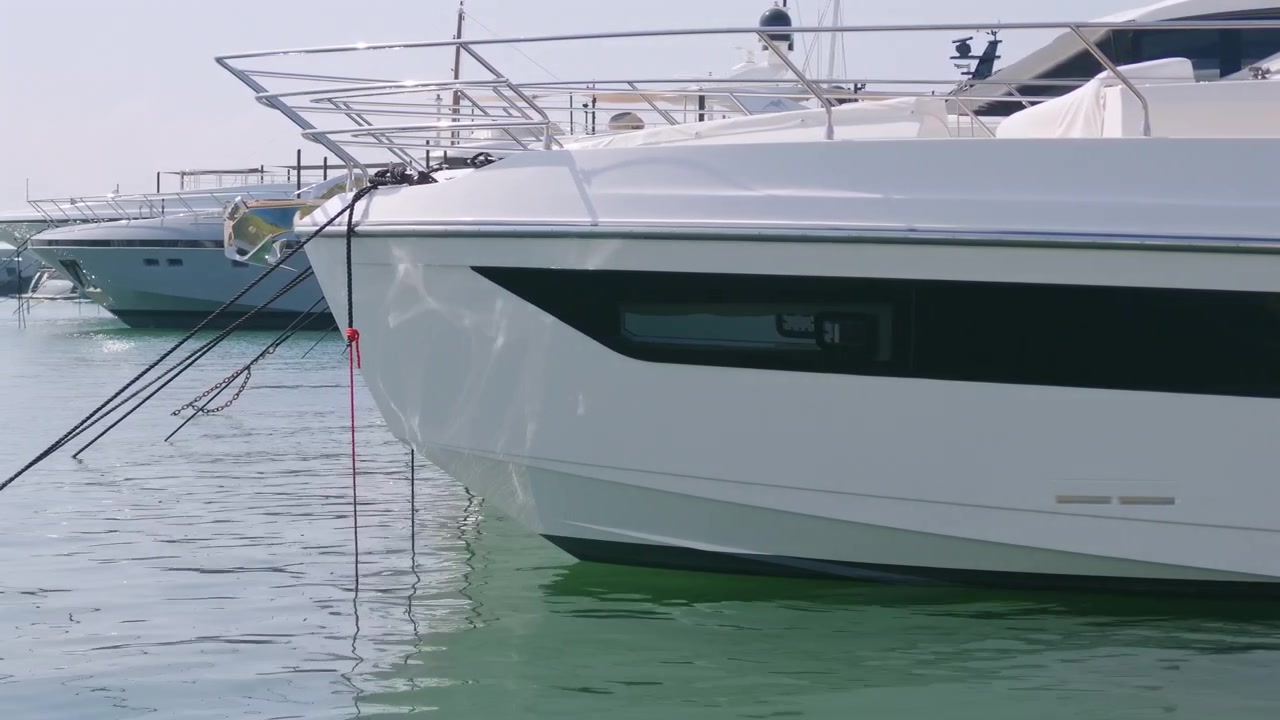 Primo piano della prua di uno yacht con cime d'ormeggio tra superyacht ormeggiati in un porto turistico, Golfe-Juan, Francia.