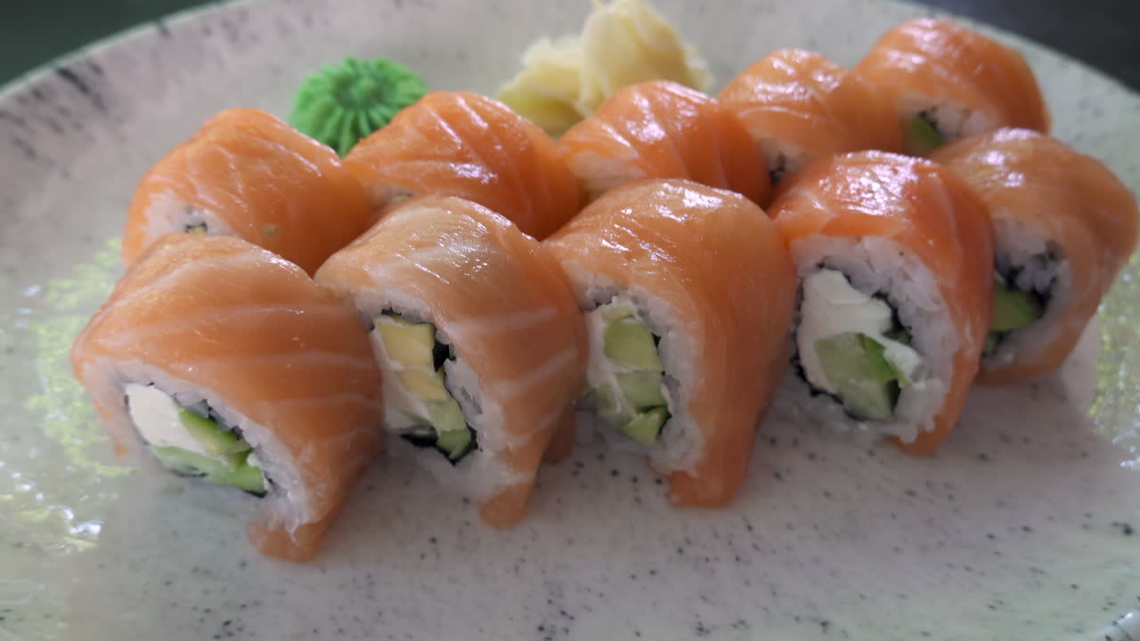 Close up of a Philadelphia sushi roll on a white plate at a restaurant