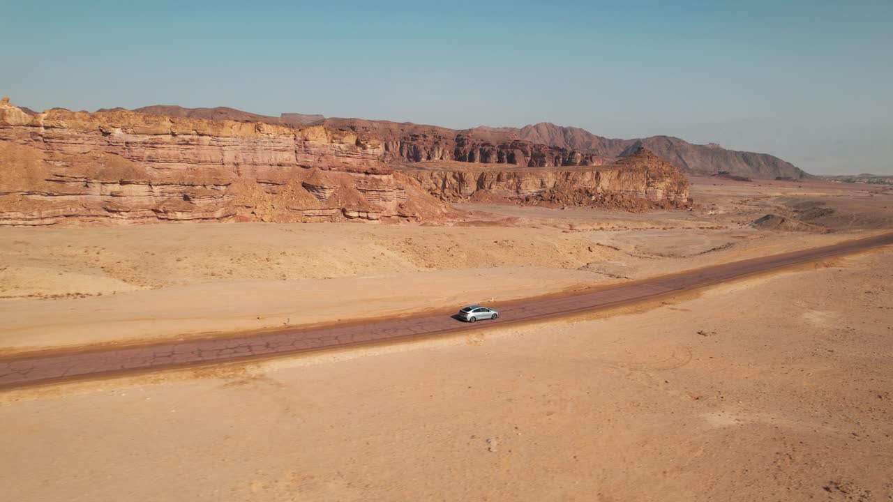 siguiente toma de drone de un automóvil conduciendo por una carretera en un gran desierto, excelente toma para transiciones a escenas desérticas