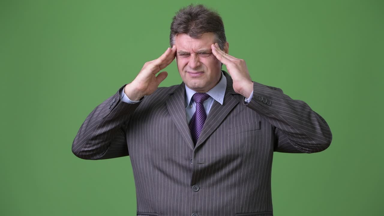 hombre de negocios maduro y guapo contra un fondo verde