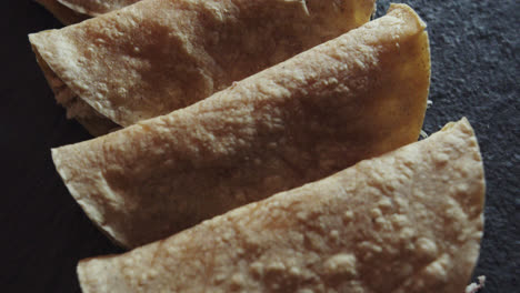 Amazing-slow-motion-Close-up-shot-of-a-group-of-4-tacos-or-Mexican-tortillas-with-chicken-placed-on-a-black-plate-and-dimly-lit