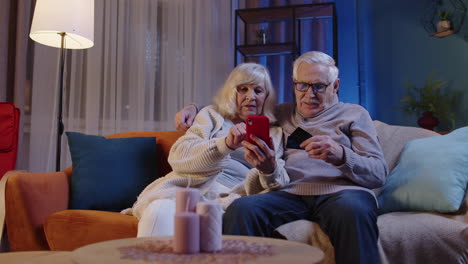 Senior-family-couple-with-smartphone-at-home,-making-online-shopping-with-credit-plastic-bank-cards