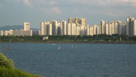 Korean-people-Windsurfing-on-Han-river,-Jamsil,-Ttukseom-Park-surf-club,-Seoul-South-Korea---daytime-static-elevated-view