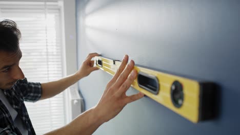 Tracking-video-of-man-using-level-on-the-blue-wall.