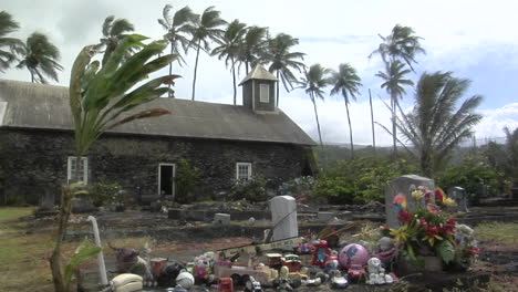 wind blows over a heavily decorated grave on a tropical island