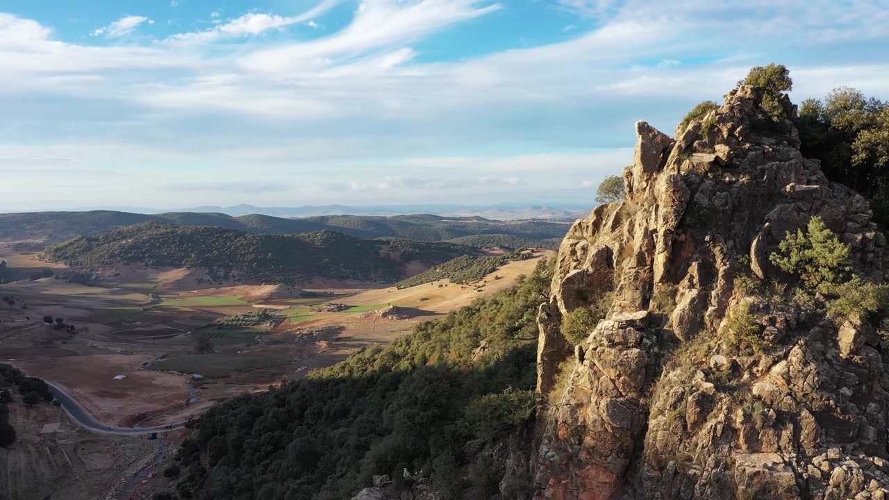 Riprese aeree cinematografiche con drone di una spettacolare scogliera rocciosa che domina vasti paesaggi di valli montane nell'Atlante Medio, Marocco, ideali per progetti di documentari di viaggio, avventura e natura.