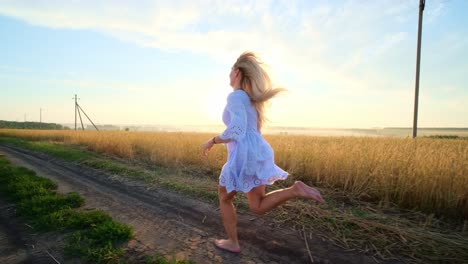 woman running barefoot through wheat field at sunrise