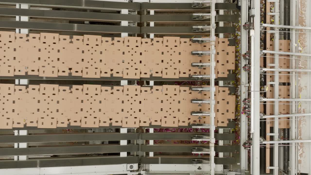 DRONE: TOP-DOWN VIEW OF CARD BOARD BOX MACHINE WORKING AT FULL CAPACITY