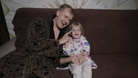 small daughter with her father watching interesting film with great emotions