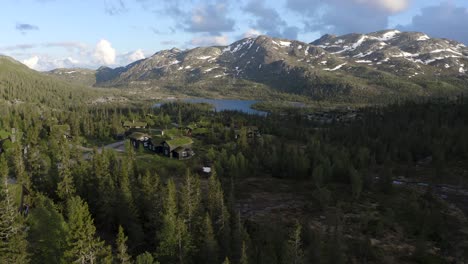 flying drone over traditional norwegian mountain cabins push in towards lake 4k