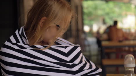 Woman-nursing-baby-in-cafe-using-milk-snood