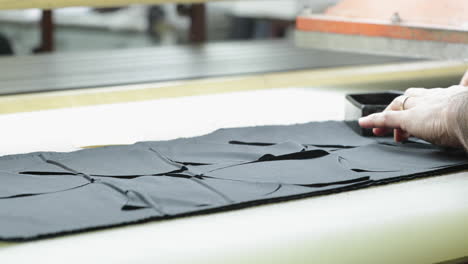 a sew factory worker placing a small metal tool making face mask patterns on fabric pressing it using the automated molder machine - covid-19 pandemic - medium shot