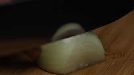 slow motion close up shot as slicing an onion on a wooden desk with a big sharp knife