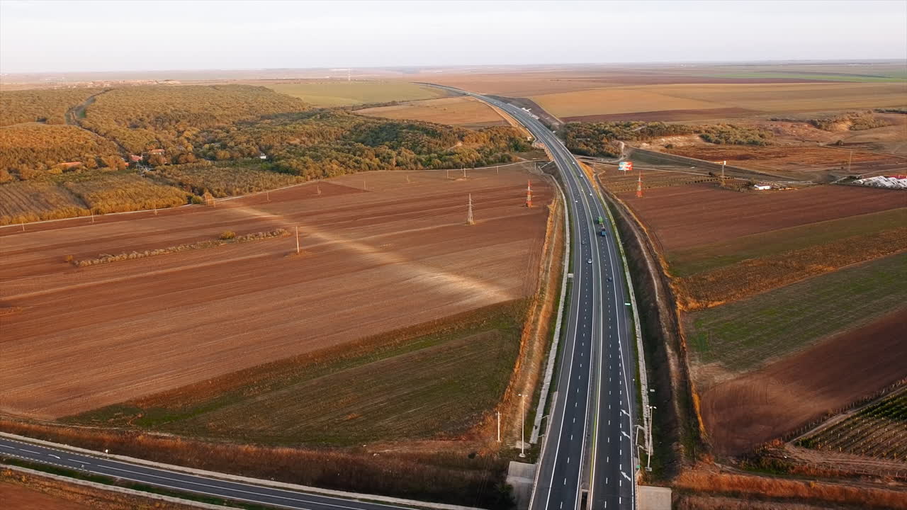 The Motorway of the Sun with moving cars crossing other road, fields around. View from the drone. Romania