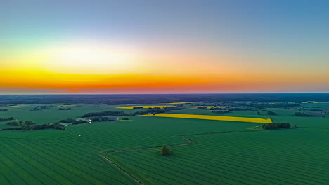 aerial view of farmlands stretching under vivid orange and blue midsummer sunset sky