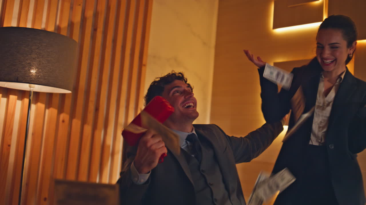 Overjoyed winners throwing dollars in neon cabinet closeup. Rejoicing partners