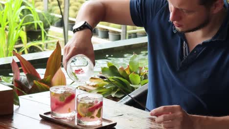 man pouring strawberry lemonade cocktails in an outdoor cafe