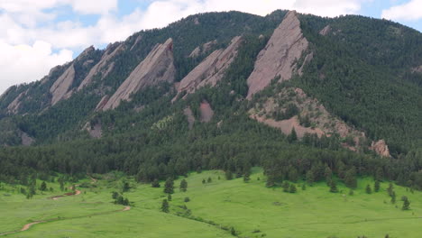 vista aérea rotativa de cerca del cálido sol golpeando boulder colorado montañas flatiron por encima del parque chautauqua con pinos verdes y cielos azules con nubes en un hermoso día de verano para hacer senderismo