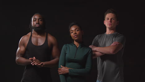 studio portrait of determined group of male and female athletes in fitness clothing training shot against black background