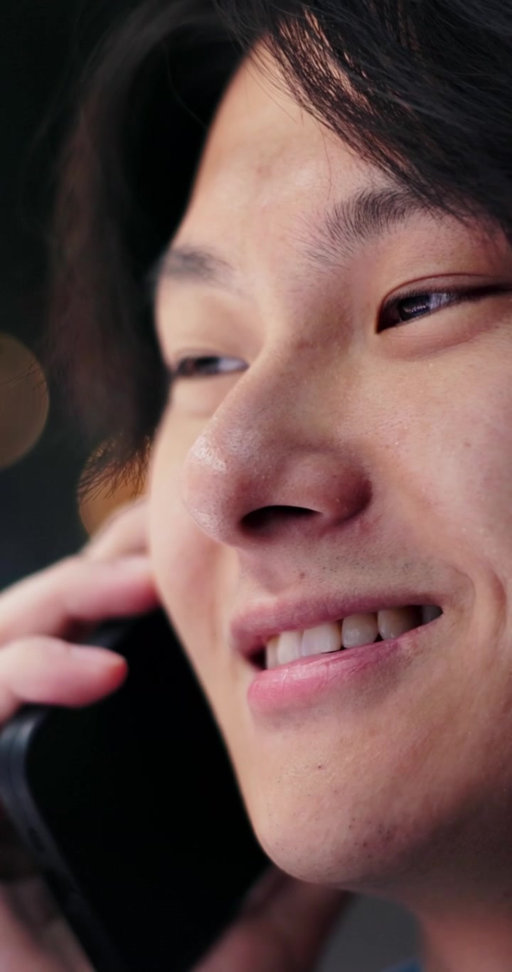 スマートフォンで話す若いアジア人男性のクローズアップ