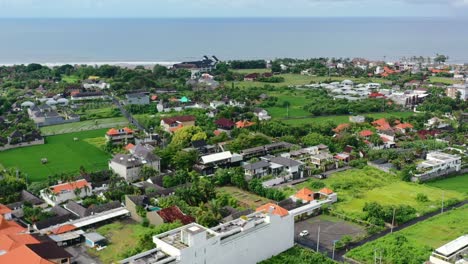 green landscape of berawa bali on cloudy day with coastline in distance, aerial