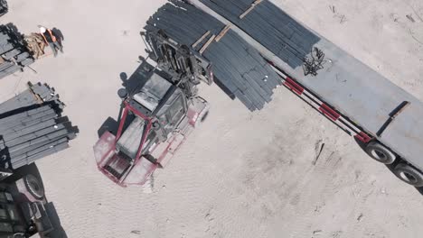 drone view of forklifts and manpower loading steel to be exported by ship