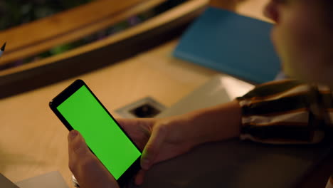 manos de una mujer usando un teléfono móvil de pantalla verde