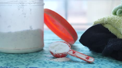 Washing-powder-in-plastic-spoon-on-blue-background-,