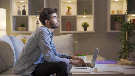 el hombre que se centra en la computadora tiene una expresión seria. en casa por la noche.
