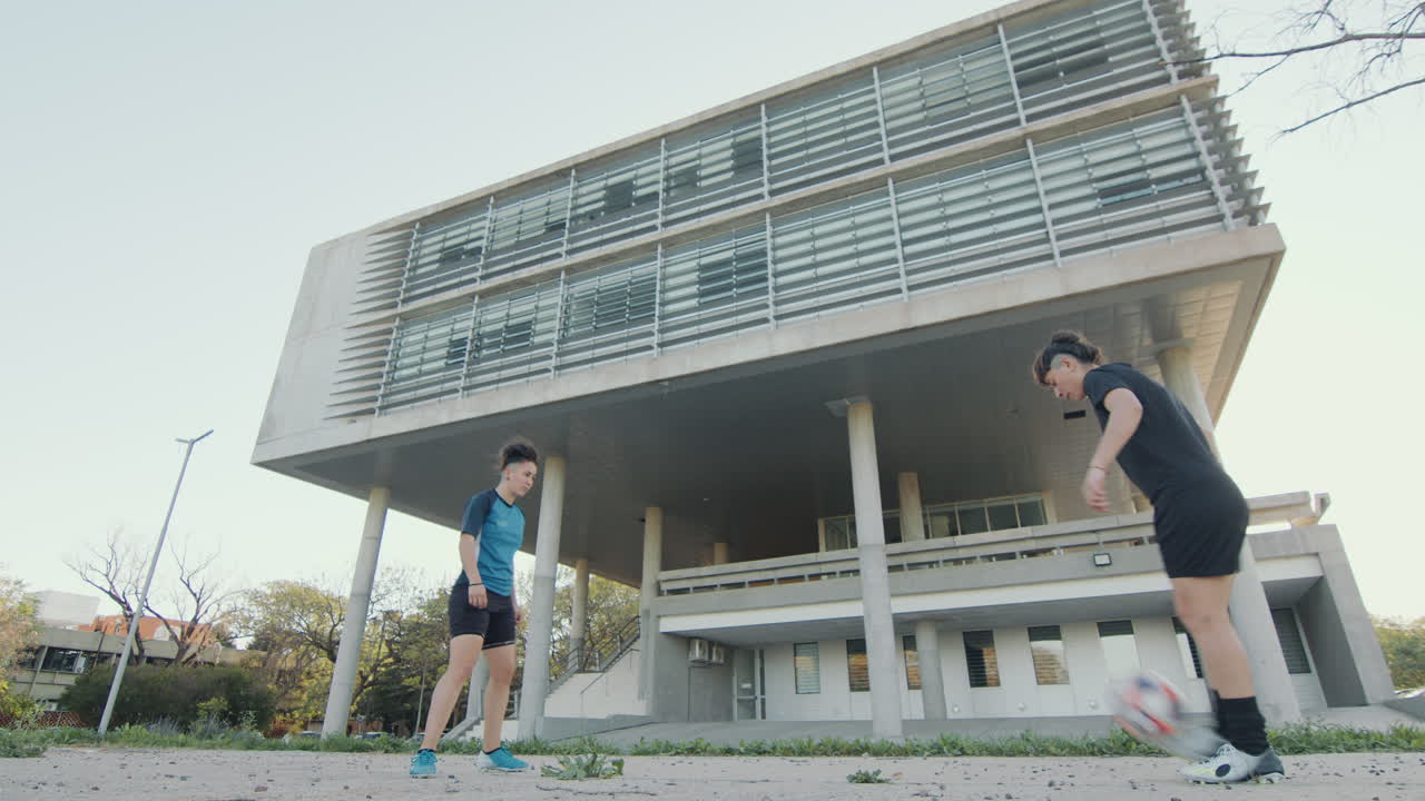 dos chicas de fútbol entrenando con la pelota en la calle