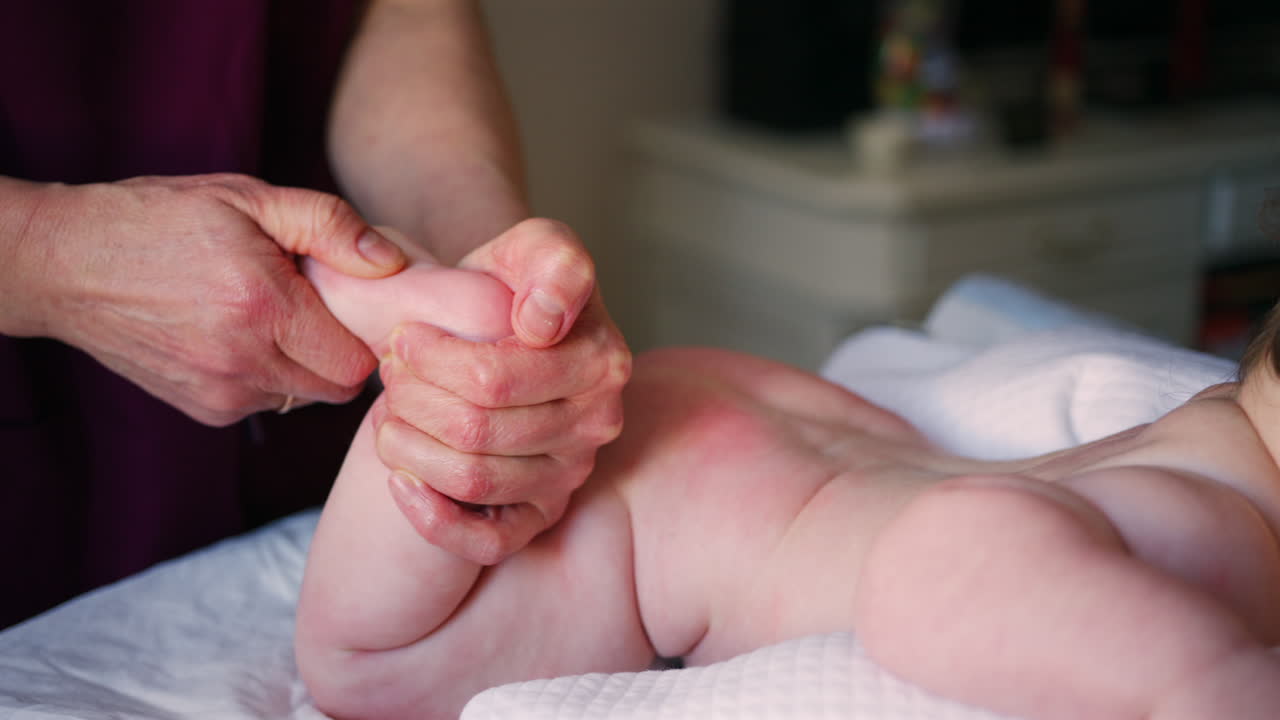 Close up of adult hands gently massaging a baby's foot and sole