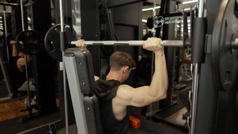 sporty man doing shoulder press exercise in smith machine