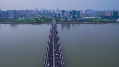 Aerial-footage-of-busy-traffic-road-highway-River-Bridge-and-modern-city-skyline-over-green-mountain-natural-landscape-in-Hangzhou,-China